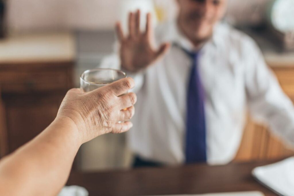 Recovering alcoholic refusing an alcoholic drink from a friend